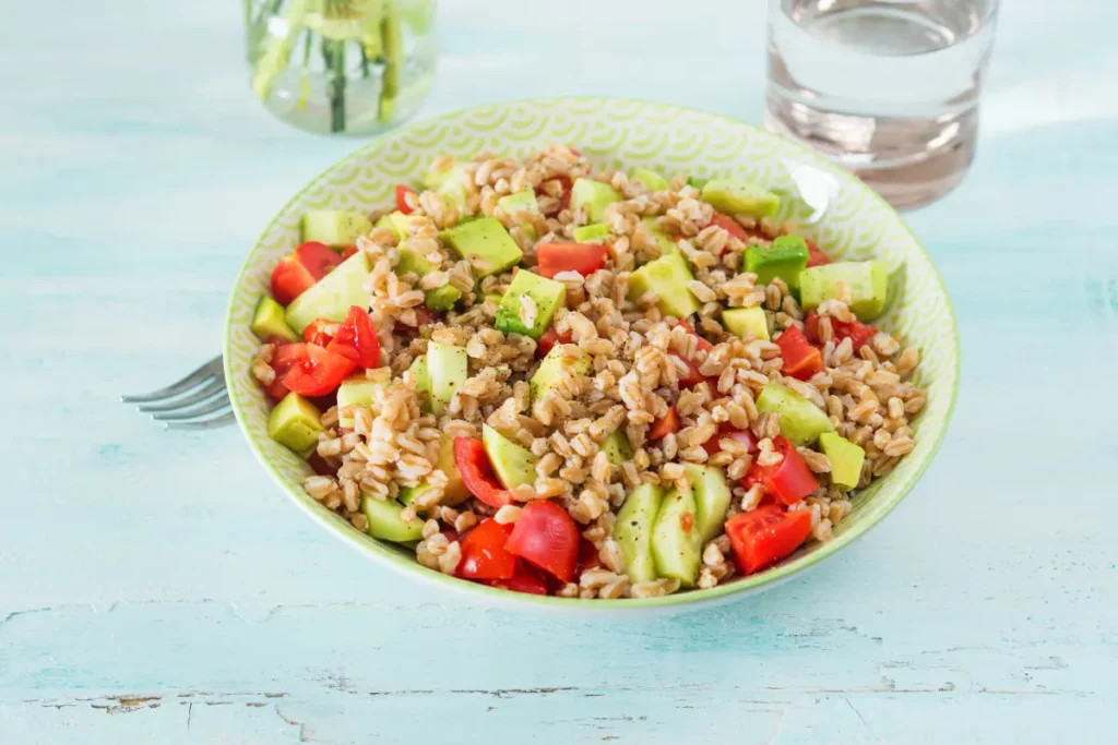 Plated Farro with Blistered Tomatoes and Green Pesto Garnished with Fresh Herbs"