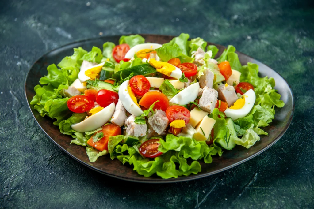 Variety of colorful fresh salads with greens, fruits, and nuts on a table.